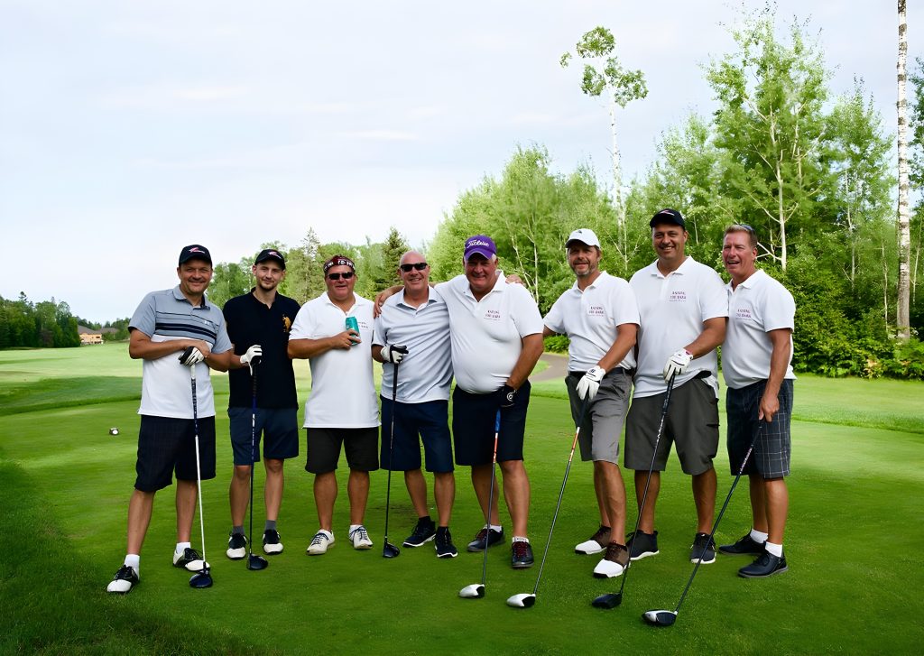 Several men participating in the charity stand on a golf course, smiling